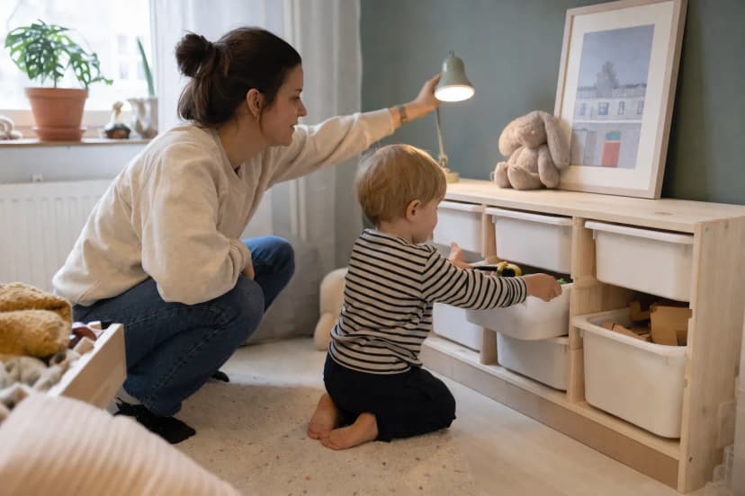 Förälder och barn ordnar förvaringskorgar och läslampa i ett flexibelt barnrum
