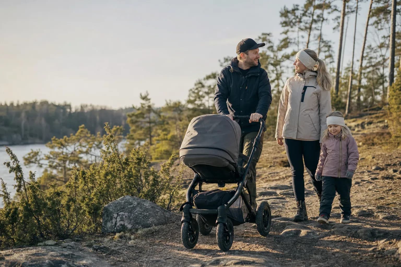 Familj promenerar med barnvagn på en skogsväg
